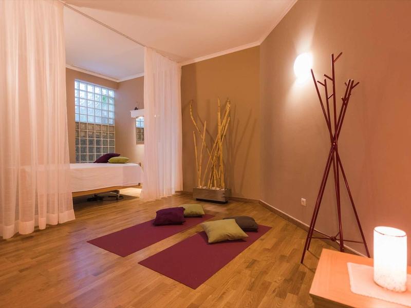 Espace yoga confortable dans une chambre d'hôtel éclairée chaleureusement avec sol en bois et rideaux.
