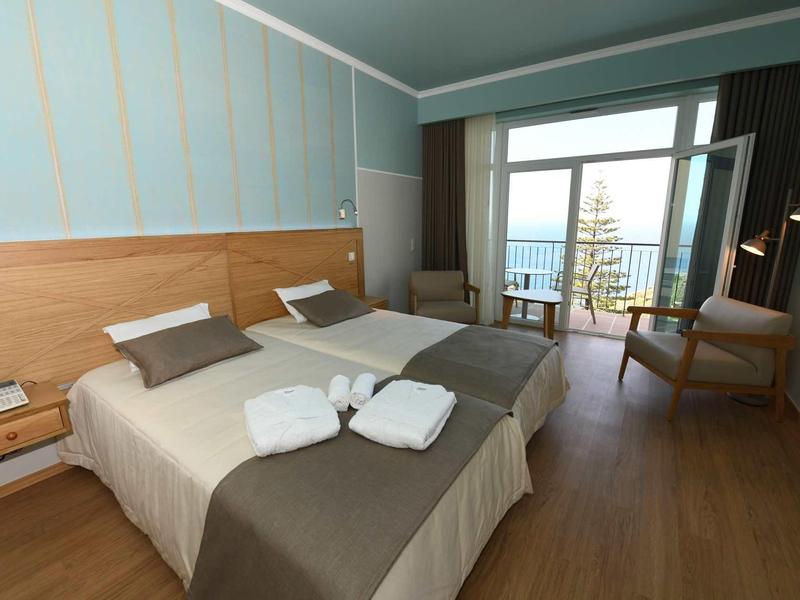 Chambre d'hôtel moderne avec deux lits, balcon et vue sur la mer.