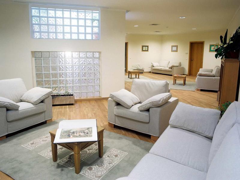 Salon lumineux et confortable avec canapés blancs, fauteuils et sol en bois clair.