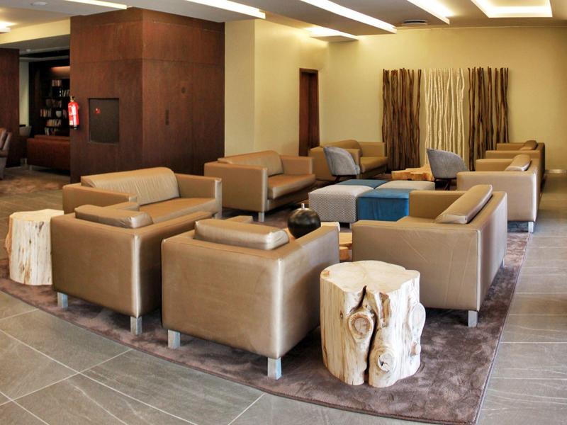 Area lounge dell'hotel moderna con poltrone beige e tavolini in legno.
