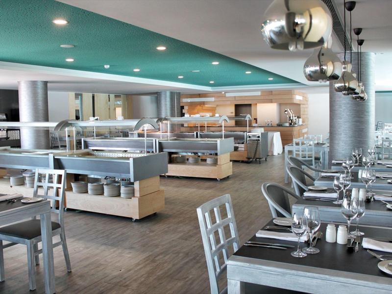 Ristorante moderno e ben illuminato con tavoli eleganti e area buffet.
