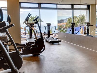 Heller Fitnessraum mit mehreren Cardiogeräten und großem Fenster mit Blick nach draußen.