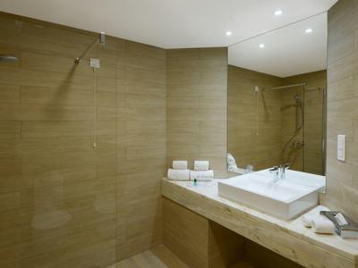 Modernes Badezimmer mit großer Spiegelwand, rechteckigem Waschbecken und offener Dusche.