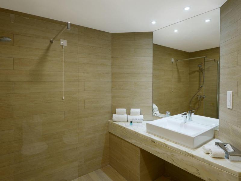 Moderne badkamer met bruine tegels, inloopdouche en grote wastafel met spiegel