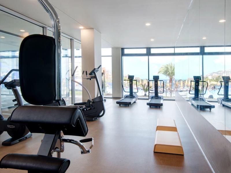 Moderne fitnessruimte met verschillende trainingsapparaten en grote ramen met uitzicht.