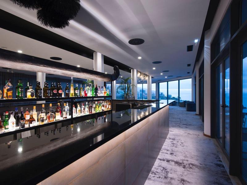 Moderne hotelbar met lange balies, sfeerverlichting en uitzicht op zee.