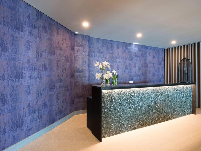 Moderne hotelreceptie met blauw versierde muur en verlicht balie