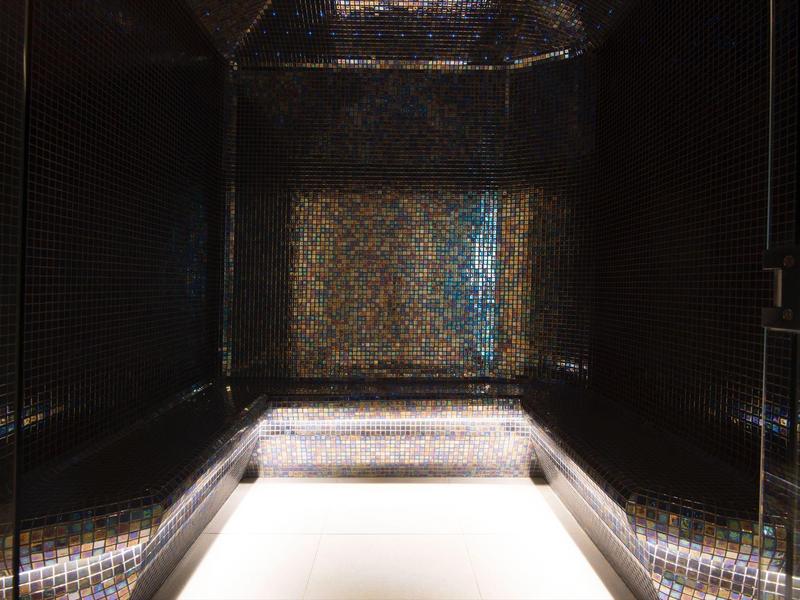 Interieur van een stijlvolle wellnessruimte met donkere mozaïekmuren en verlichtte vloer