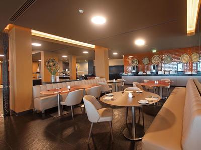 Modernes Café mit beigen Sitzbänken, runden Tischen und warmem, indirektem Licht.