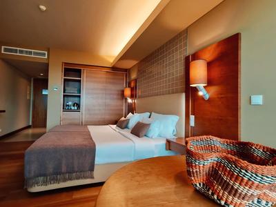 Modernes Hotelzimmer mit großem Bett, Holzmöbeln und warmem Licht.