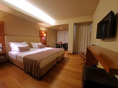 Modernes Hotelzimmer mit Doppelbett, Holzboden, Wandfernseher und Schreibtisch.