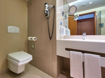 Modernes Bad mit wandhängendem WC, großem Spiegel, Waschbecken und Handtüchern.