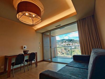 Hell eingerichteter Raum mit blauem Sofa, Holztisch, zwei Stühlen und großem Fenster mit Balkonblick.