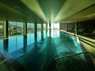 Heller Innenpool mit großflächigen Fenstern und Blick auf Stadt und Landschaft bei Tageslicht.