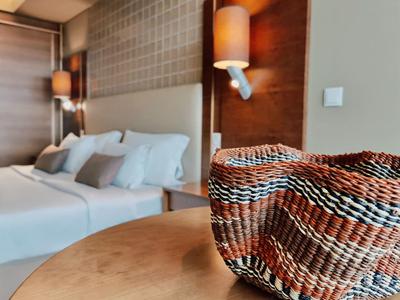 Ein geflochtener Korb steht auf einem runden Holztisch in einem Hotelzimmer mit Doppelbett.