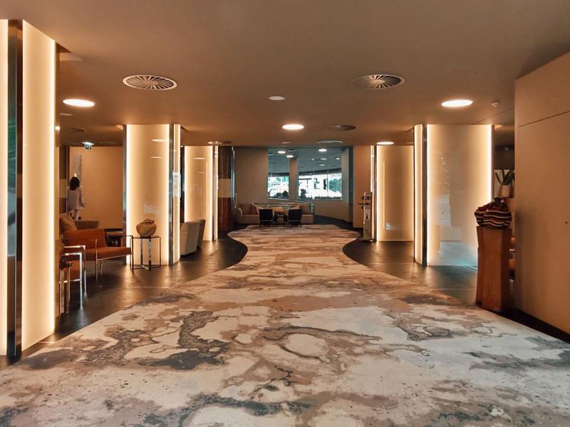 Moderner Hotelflur mit warmem Licht, Teppichboden und abgerundeten Wänden, elegant und einladend.