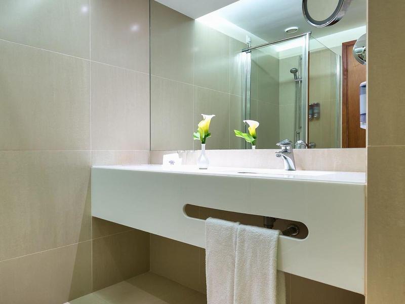 Helles, modernes Badezimmer mit großer Spiegelwand, Doppelwaschbecken und hellem Fliesenboden.