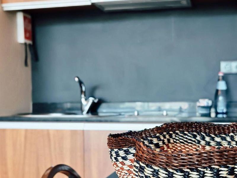 Küchenzeile mit Holzmöbeln, schwarzer Arbeitsplatte, Spüle und geflochtenem Korb auf Tisch.