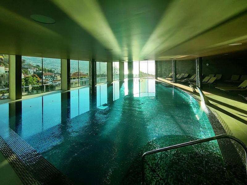 Heller Innenpool mit großflächigen Fenstern und Blick auf Stadt und Landschaft bei Tageslicht.