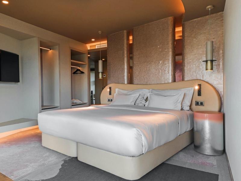 Modernes Schlafzimmer mit großem Bett, eingebautem Kleiderschrank und warmem Deckenlicht.