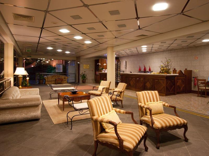 Accogliente area lounge dell'hotel con poltrone, divano, tavoli e illuminazione soffusa.