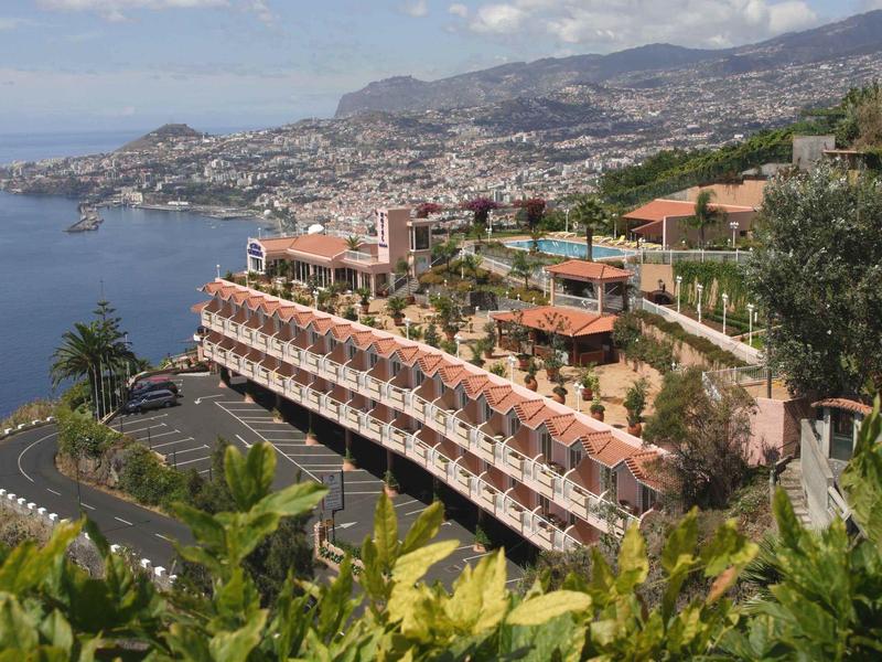 Complesso alberghiero sulla collina con vista sulla costa e sulla città lontana.