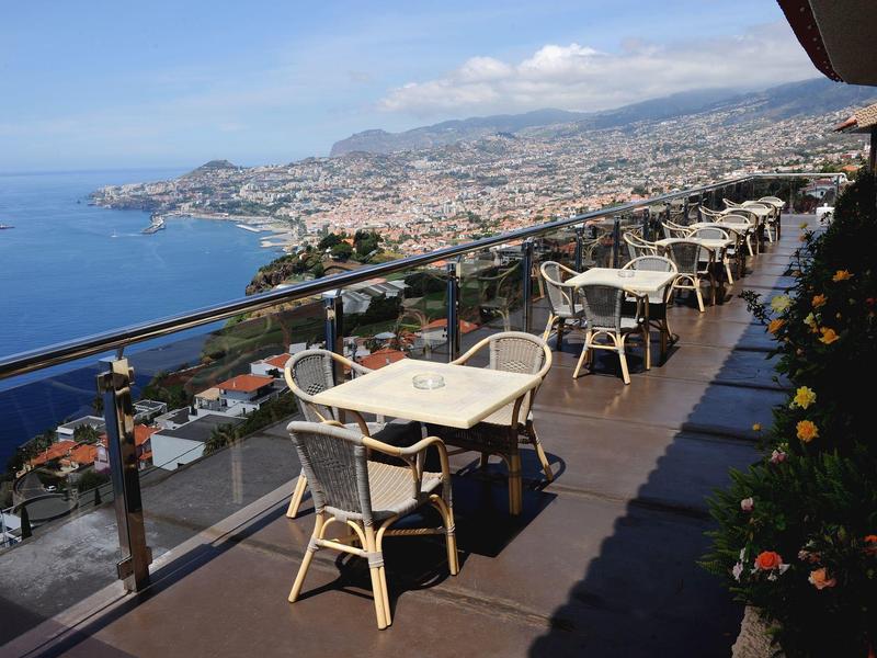 Terrazza con tavoli e sedie con vista sul mare e sulla città