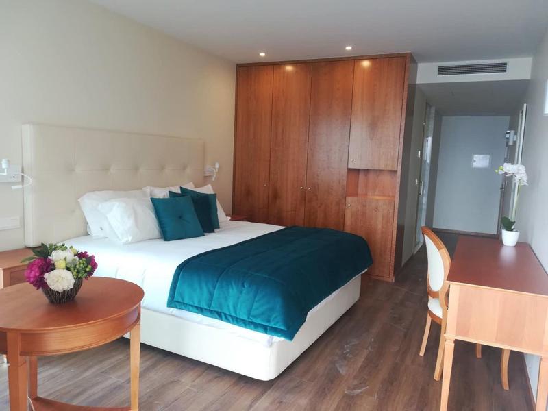 Camera d'albergo moderna con letto matrimoniale, mobili in legno e scrivania.