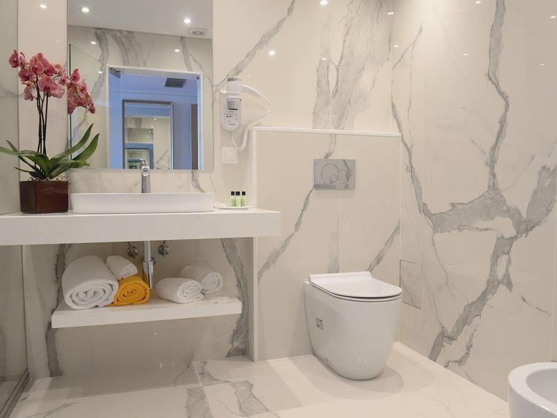 Bagno moderno con lavabo bianco, WC e piastrelle in marmo.