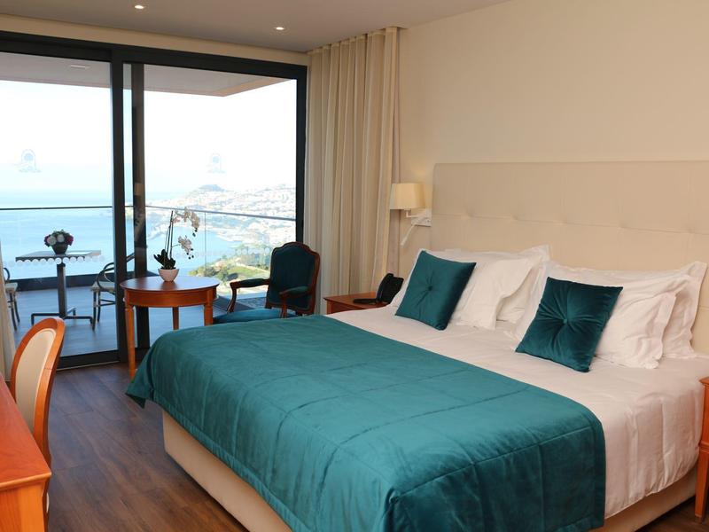 Camera d'hotel moderna con letto matrimoniale, balcone e vista mare