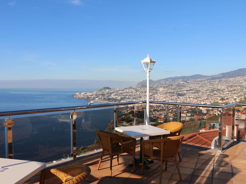 Terrazza con tavoli e sedie con vista sul mare e sulla città costiera.