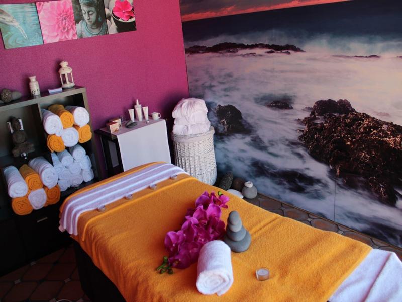 Accogliente sala trattamenti con lettino da massaggio, asciugamani freschi e murale oceanico rilassante.