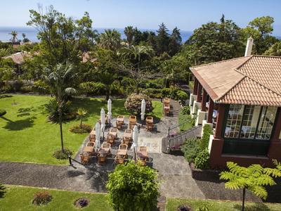 Aree salotto nel giardino accanto a un edificio con vista sull’oceano sotto un cielo sereno.