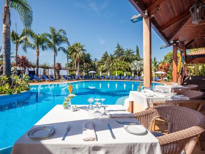 Tavolo con tovaglia bianca accanto a una piscina in un hotel tropicale soleggiato.