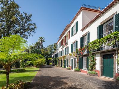 Edificio dell'hotel su più piani con persiane verdi e vegetazione rigogliosa nel giardino