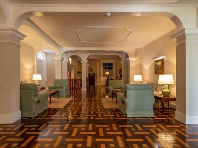 Elegante hall dell'hotel con poltrone imbottite, lampade e pavimento in parquet decorativo.