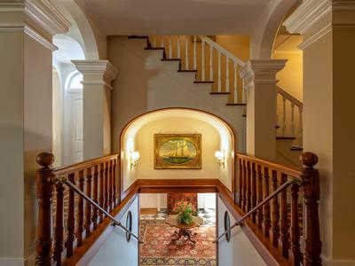 Elegante area scale con archi, corrimano in legno e illuminazione classica in un hotel.