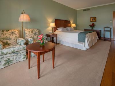 Camera d'hotel accogliente con letto matrimoniale, poltrona, tavolo e illuminazione soffusa.