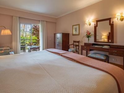 Camera d'albergo accogliente con letto grande, scrivania e vista sul giardino