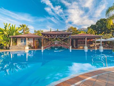 Grande piscina dell'hotel con acqua azzurra limpida e vegetazione tropicale sullo sfondo.