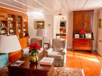 Soggiorno accogliente con poltrone, lampade e mobili in legno con decorazioni natalizie.