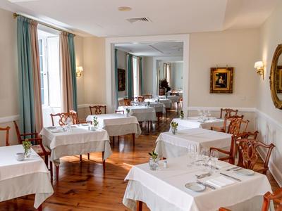 Ristorante elegante con tovaglie bianche, sedie di legno e opere d'arte alle pareti.