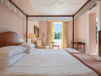 Camera d'hotel luminosa con grande letto e area salotto con vista sul balcone.