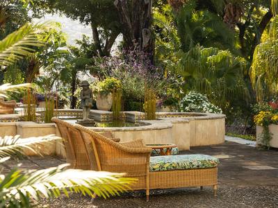 Gemütliche Outdoor-Lounge mit geflochtenen Sesseln und grüner Vegetation im Hintergrund.