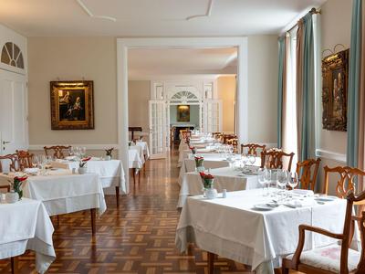 Eleganter Speisesaal mit weißen Tischdecken und braunen Holzstühlen in einem Hotel.