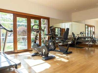 Heller Fitnessraum mit Holzfußboden, Kardio-Geräten und großen Fenstern mit Blick nach draußen.
