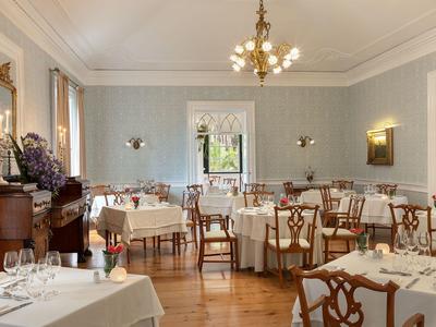 Eleganter Speisesaal mit klassischen Holzmöbeln und gedeckten Tischen in einem Hotel.