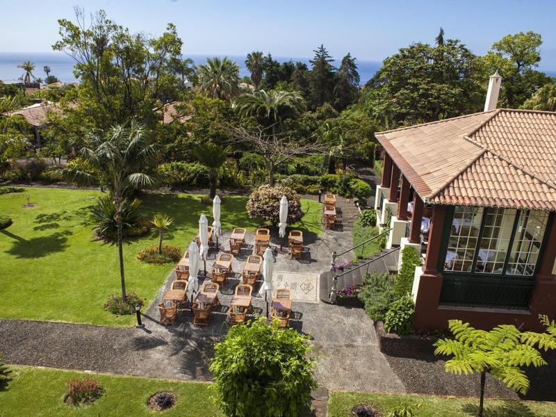 Aree salotto nel giardino accanto a un edificio con vista sull’oceano sotto un cielo sereno.