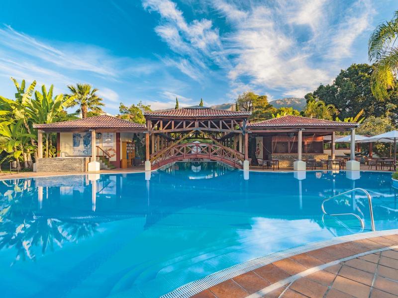 Grande piscina dell'hotel con acqua azzurra limpida e vegetazione tropicale sullo sfondo.