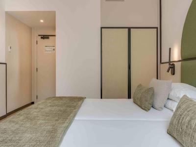 Chambre d'hôtel moderne avec lit double, accents verts et design minimaliste.